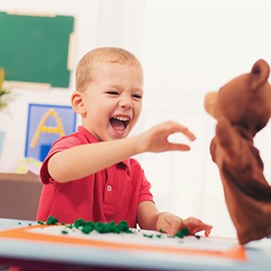 young boy laughing at hand puppet 