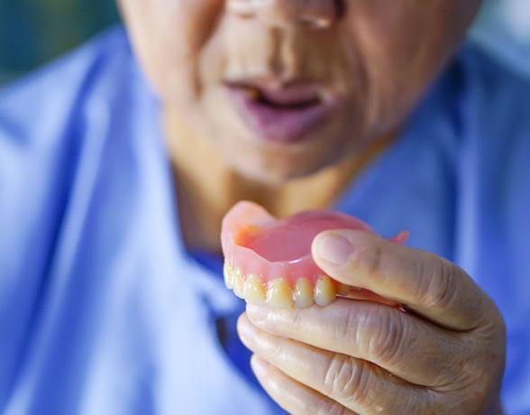 a person holding their denture before wearing them