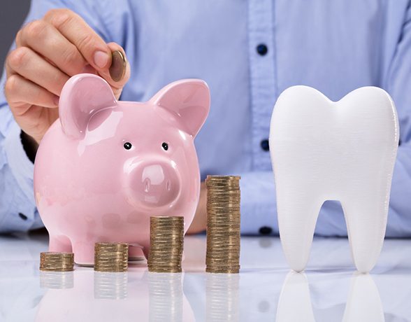 Piggy bank next to tooth and stacks of coins