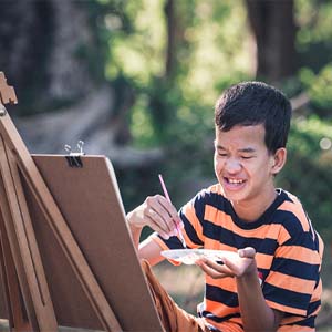 child with intellectual disability painting outside