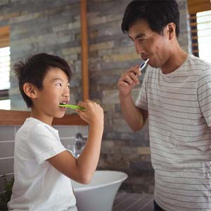 father brushing teeth with child