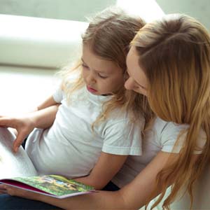 mother reading book to young daughter