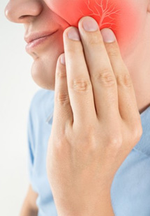 a person holding their cheek due to tooth pain
