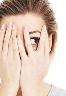 a woman covering her face and peeking through her fingers
