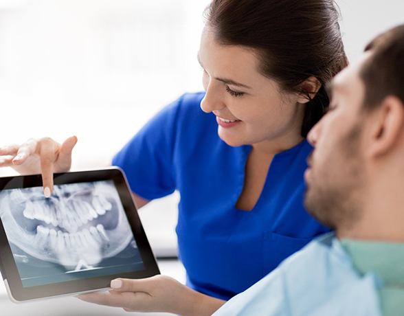 a dentist showing a patient an X-ray of teeth