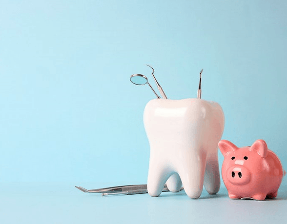 a tooth with dental tools next to a piggy bank