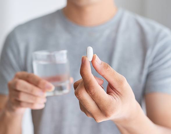 Patient holding an oral conscious dental sedation pill and glass of water