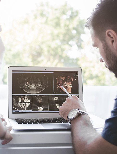 Dentist looking at digital dental x-rays on chairside computer