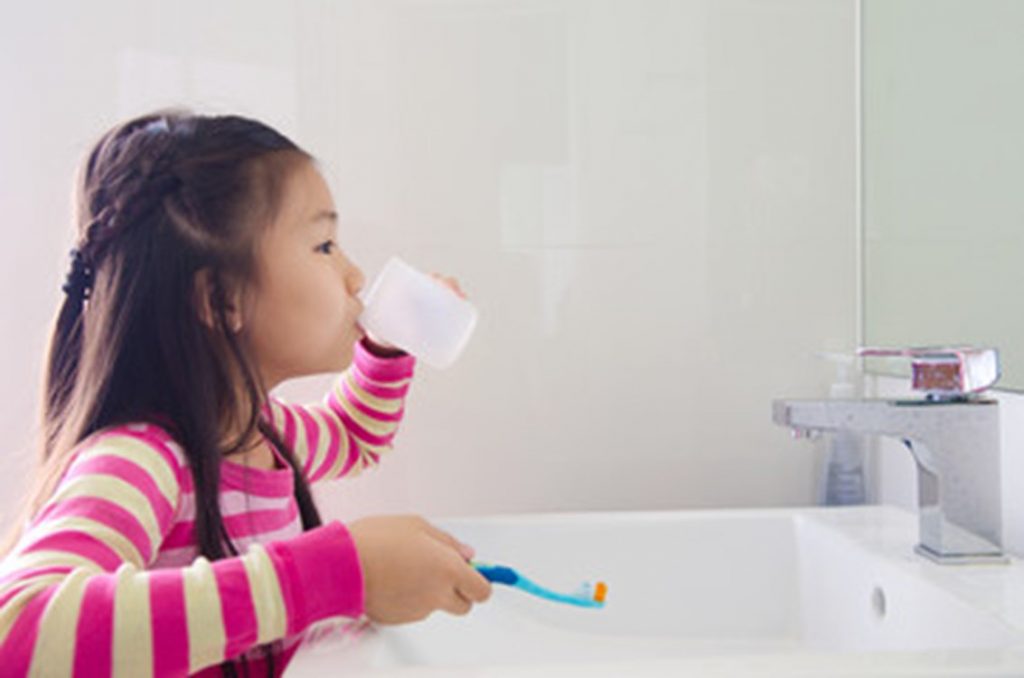 Young child brushing her teeth.