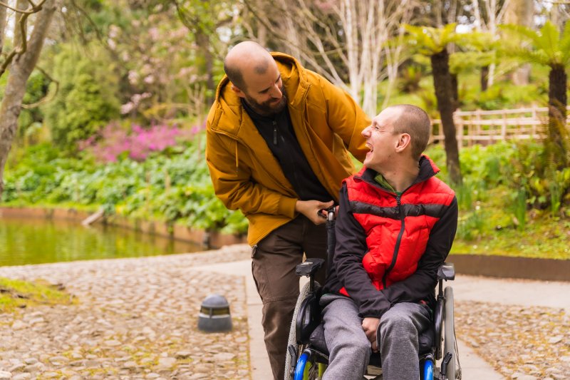 man pushing another adult male in a wheelchair