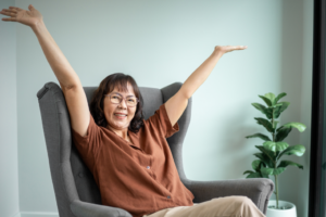 a smiling woman sitting in a chair with her hands up