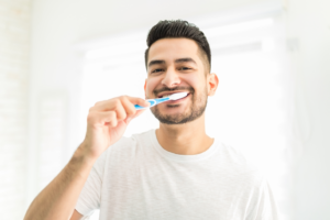 a smiling man brushing his teeth